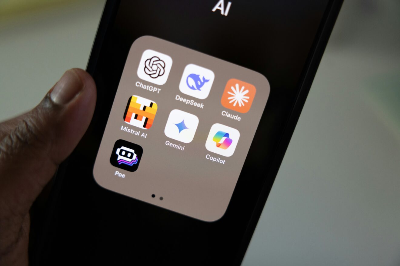 Hand holding mobile device, on screen artificial intelligence app icons